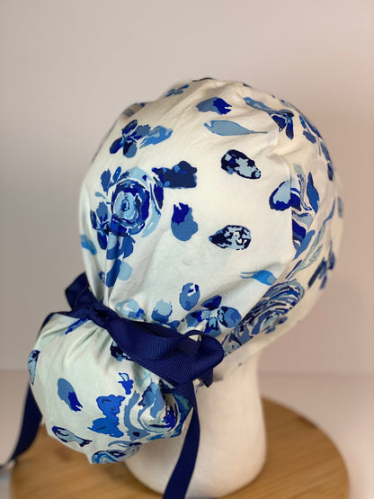 Shades of blue women’s floral scrub cap, blue, white, and navy floral ponytail scrub hat