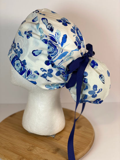 Shades of blue women’s floral scrub cap, blue, white, and navy floral ponytail scrub hat