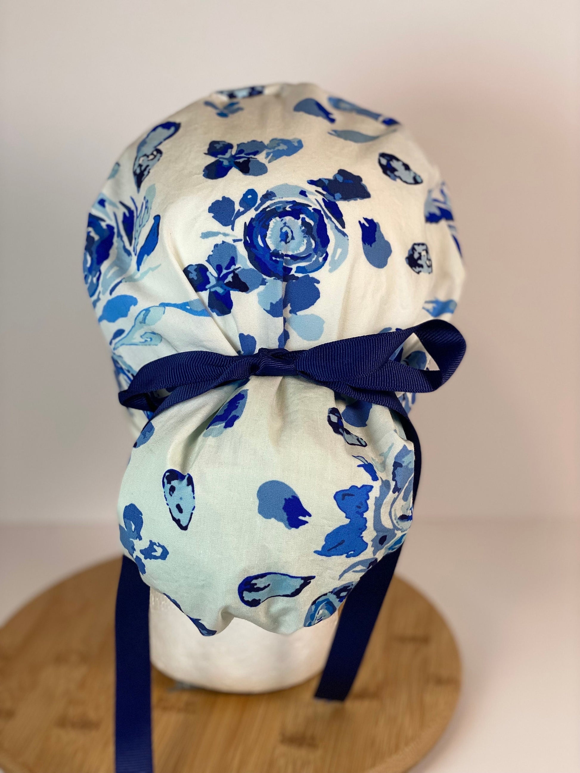 Shades of blue women’s floral scrub cap, blue, white, and navy floral ponytail scrub hat