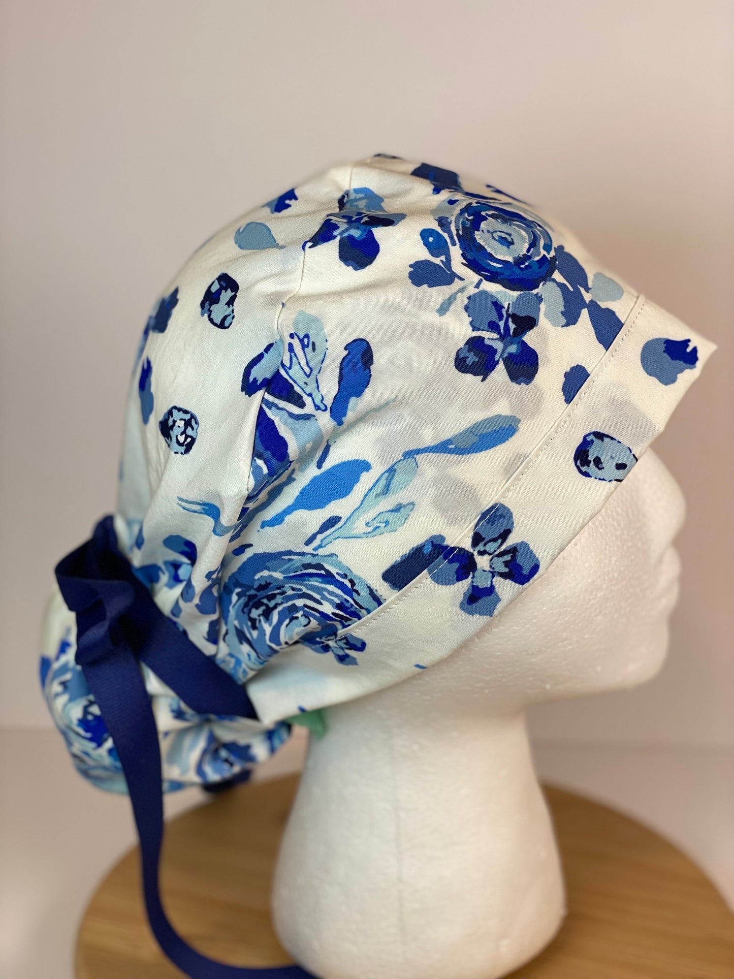 Shades of blue women’s floral scrub cap, blue, white, and navy floral ponytail scrub hat