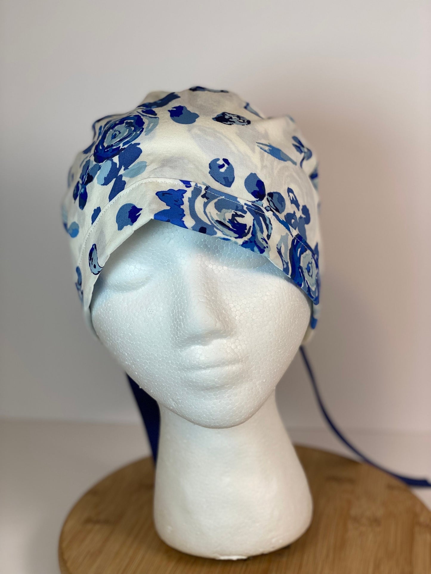 Shades of blue women’s floral scrub cap, blue, white, and navy floral ponytail scrub hat