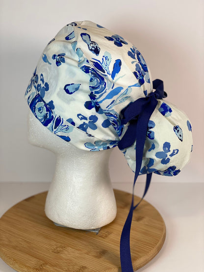 Shades of blue women’s floral scrub cap, blue, white, and navy floral ponytail scrub hat