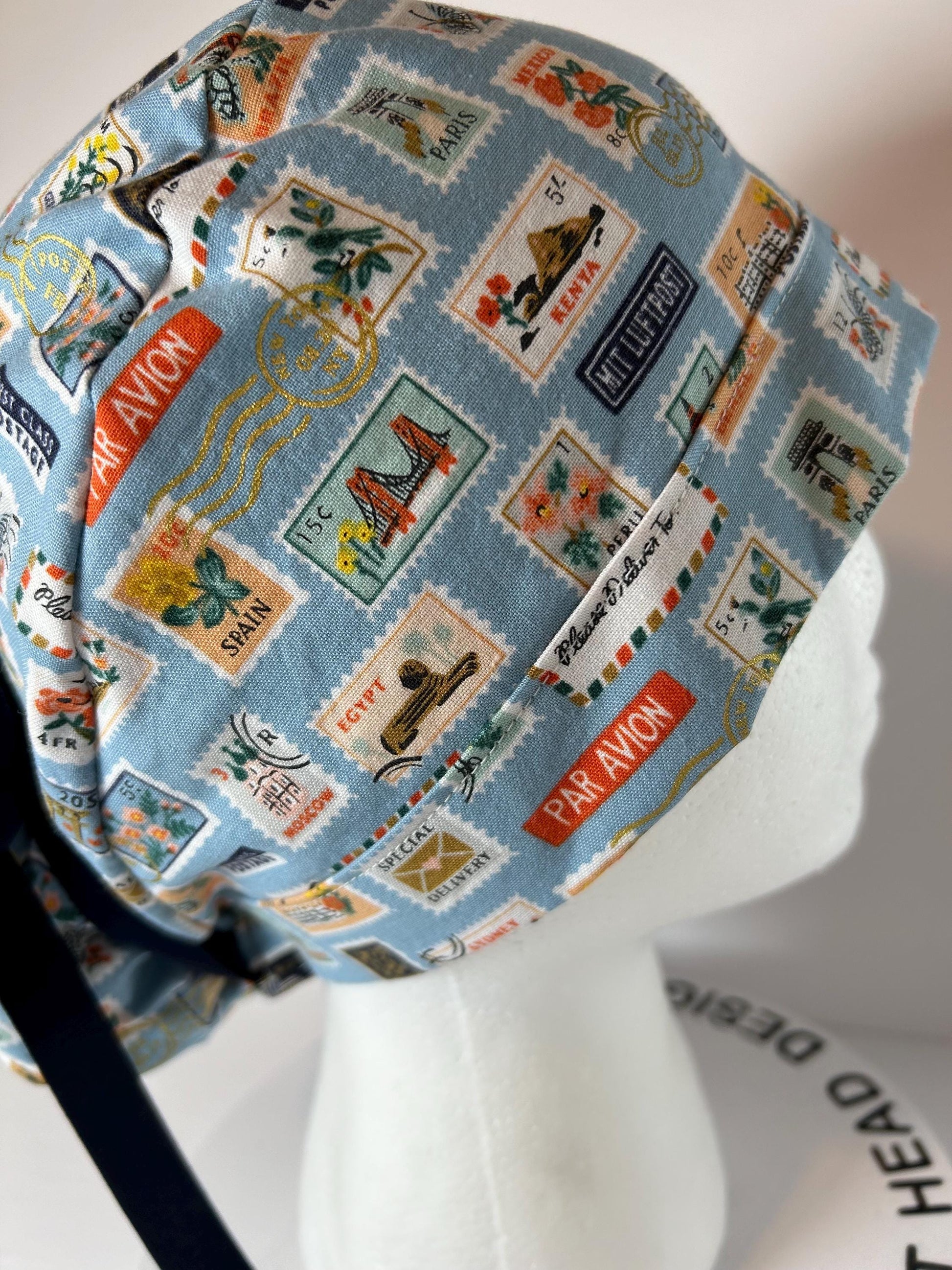 Rifle Paper travel stamp print scrub cap, blue and green travel stamps ponytail scrub hat, Bonnet Head Designs