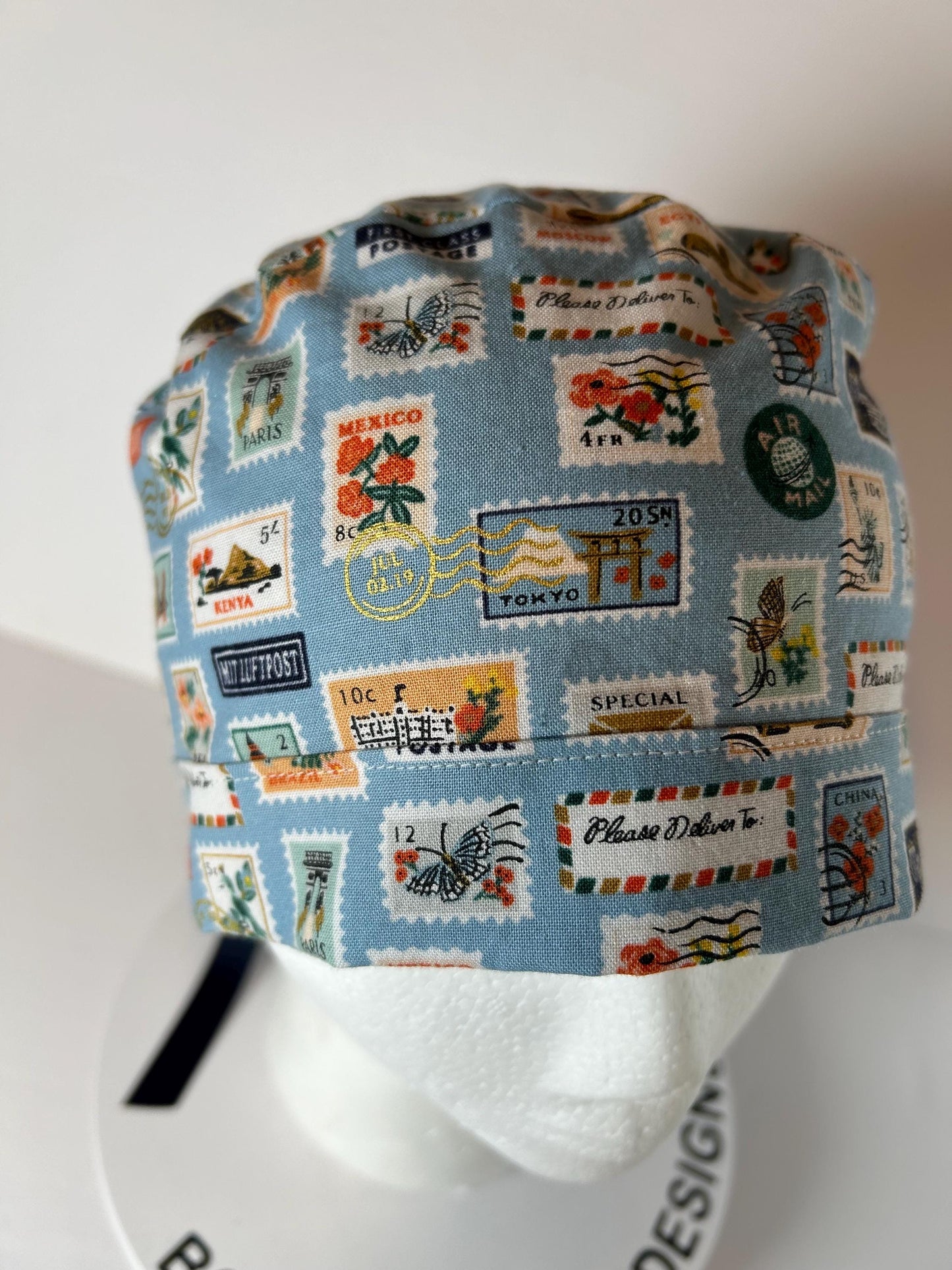 Rifle Paper travel stamp print scrub cap, blue and green travel stamps ponytail scrub hat, Bonnet Head Designs