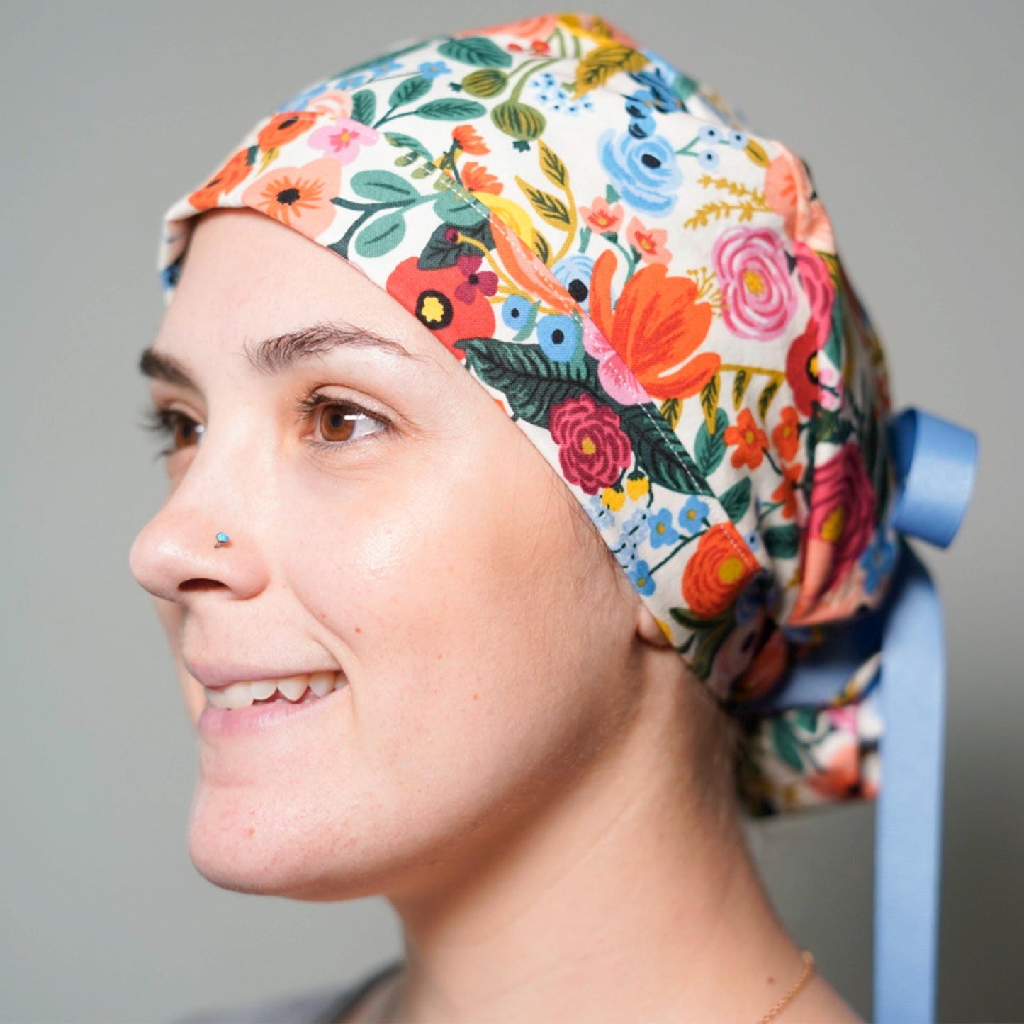 A woman wearing a colorful floral cap and smiling at the camera.