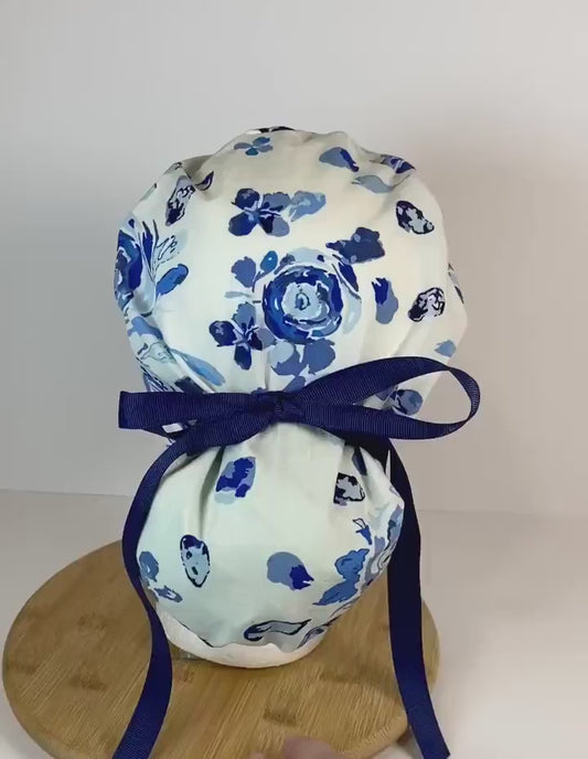 Shades of blue women’s floral scrub cap, blue, white, and navy floral ponytail scrub hat